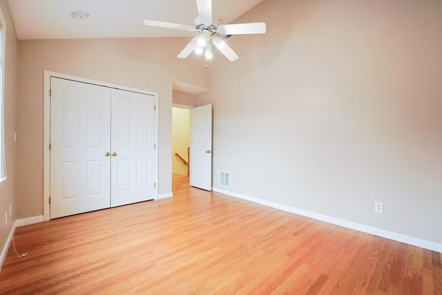 unfurnished bedroom with ceiling fan, a closet, light hardwood / wood-style floors, and vaulted ceiling