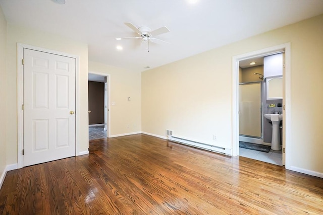 interior space featuring ensuite bathroom, ceiling fan, wood-type flooring, and a baseboard heating unit