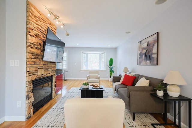 living room with a fireplace, rail lighting, and light hardwood / wood-style floors