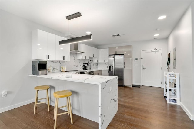 kitchen featuring visible vents, a peninsula, dark wood finished floors, and stainless steel fridge with ice dispenser