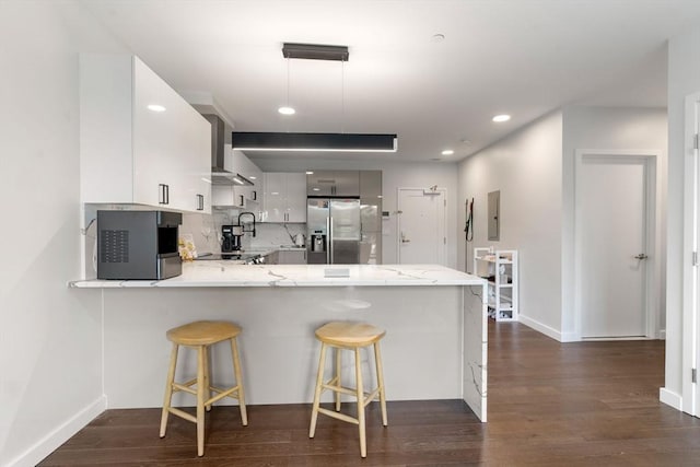 kitchen with tasteful backsplash, electric panel, a peninsula, stainless steel fridge, and dark wood-style flooring