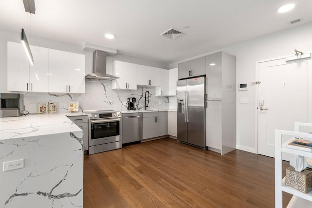 kitchen featuring decorative backsplash, dark wood-type flooring, appliances with stainless steel finishes, and wall chimney range hood