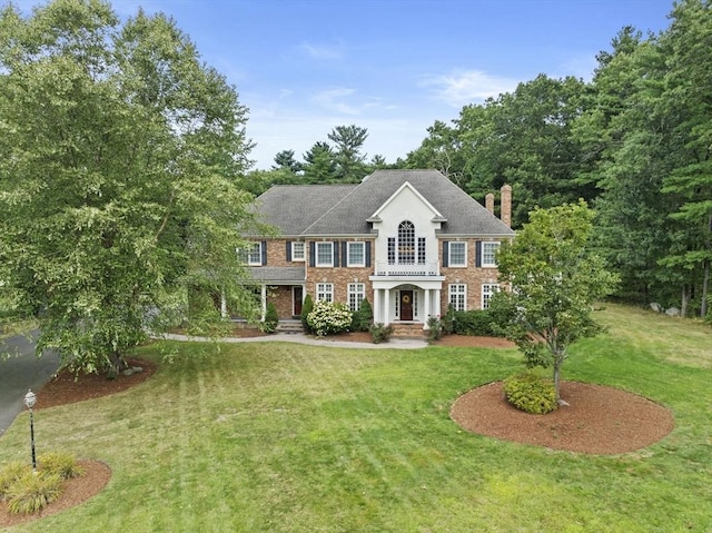 view of front of property with a front lawn, a chimney, and a balcony