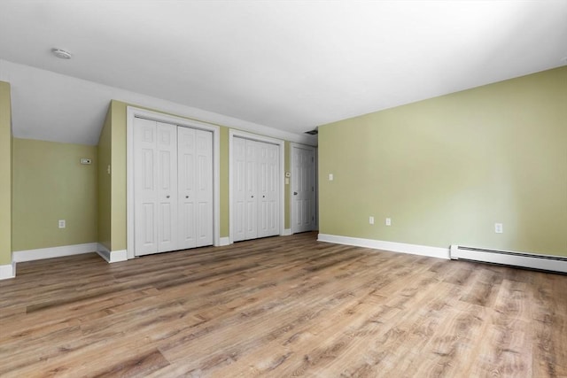 17 Topsfield Rd, Wenham, MA 01984 - unfurnished bedroom featuring multiple closets, baseboards, wood finished floors, baseboard heating, and vaulted ceiling