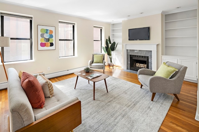 living room featuring crown molding, a high end fireplace, light hardwood / wood-style flooring, a baseboard heating unit, and built in shelves