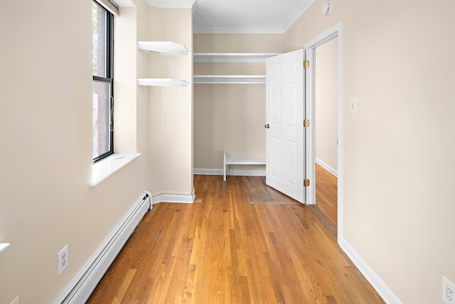 interior space with light wood-type flooring, a closet, baseboard heating, and ornamental molding