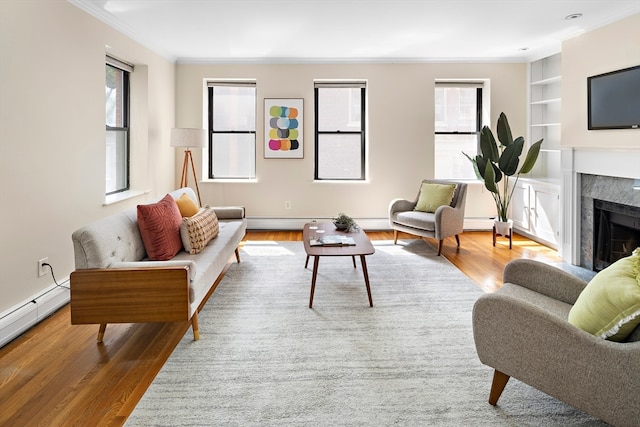 living room featuring built in features, crown molding, baseboard heating, and wood-type flooring