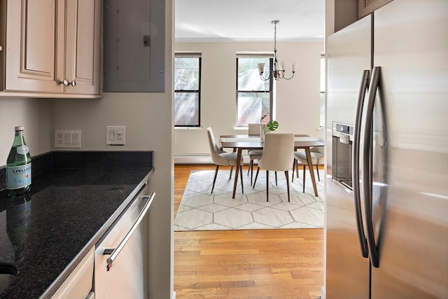 kitchen with a chandelier, light hardwood / wood-style flooring, decorative light fixtures, electric panel, and appliances with stainless steel finishes