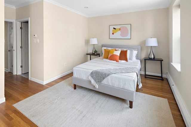 bedroom with hardwood / wood-style flooring, baseboard heating, and ornamental molding