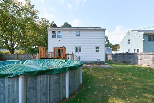 back of house featuring a yard and a covered pool