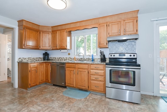 kitchen with light stone countertops, appliances with stainless steel finishes, sink, and decorative backsplash