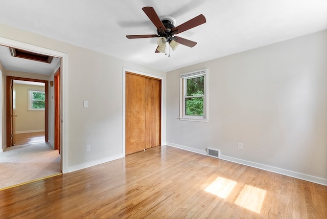 unfurnished bedroom with light wood-type flooring, ceiling fan, and a closet