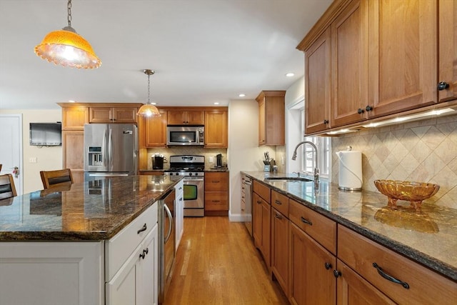 128 S Sea Ave, Yarmouth, MA 02673 - kitchen featuring stainless steel appliances, brown cabinetry, light wood-type flooring, tasteful backsplash, and decorative light fixtures