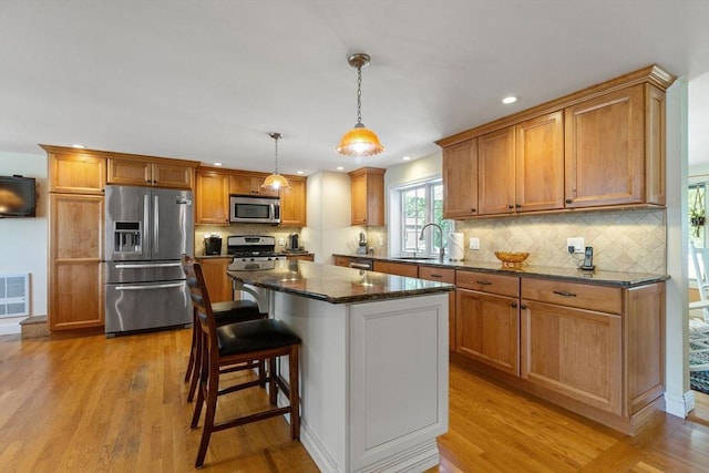 128 S Sea Ave, Yarmouth, MA 02673 - kitchen featuring stainless steel appliances, light wood-style flooring, tasteful backsplash, dark stone counters, and recessed lighting