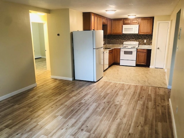 kitchen with white appliances, decorative backsplash, and light hardwood / wood-style flooring