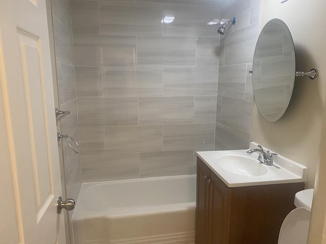 full bathroom featuring vanity, tiled shower / bath combo, and toilet