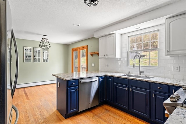 kitchen with a baseboard heating unit, a sink, a peninsula, blue cabinetry, and stainless steel appliances