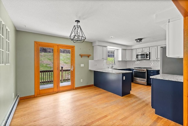 kitchen with a baseboard radiator, stainless steel appliances, light wood-style flooring, and a peninsula