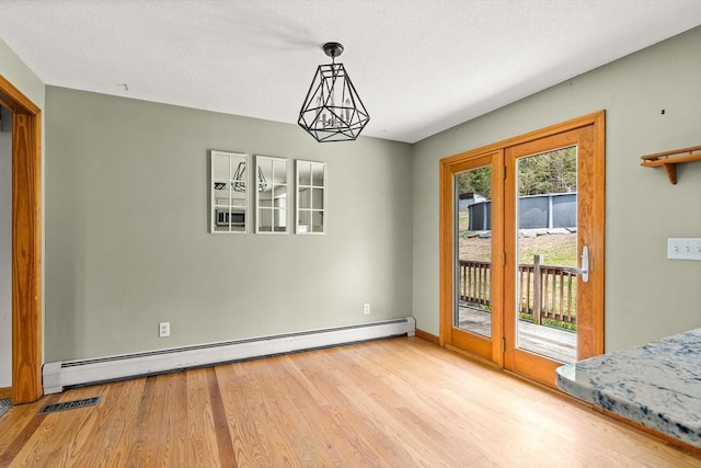 unfurnished dining area featuring baseboards, a baseboard radiator, visible vents, and wood finished floors