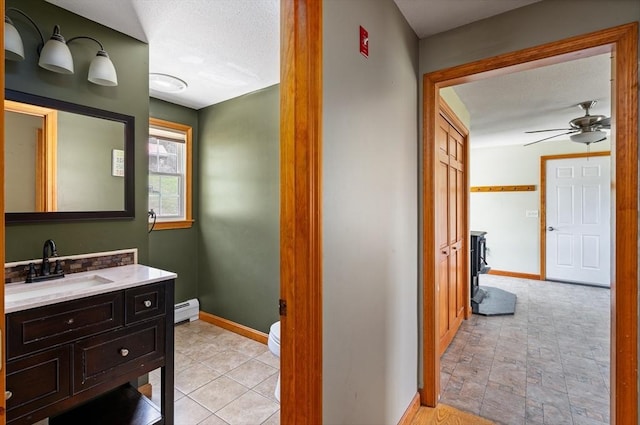 bathroom featuring a baseboard radiator, baseboards, a ceiling fan, and vanity
