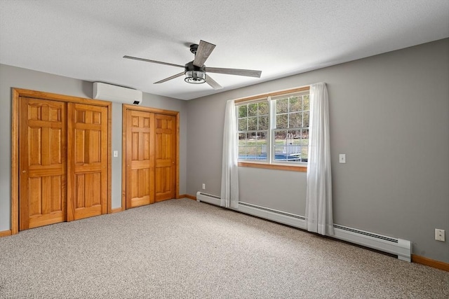 unfurnished bedroom featuring a wall mounted air conditioner, carpet flooring, baseboards, and a baseboard heating unit