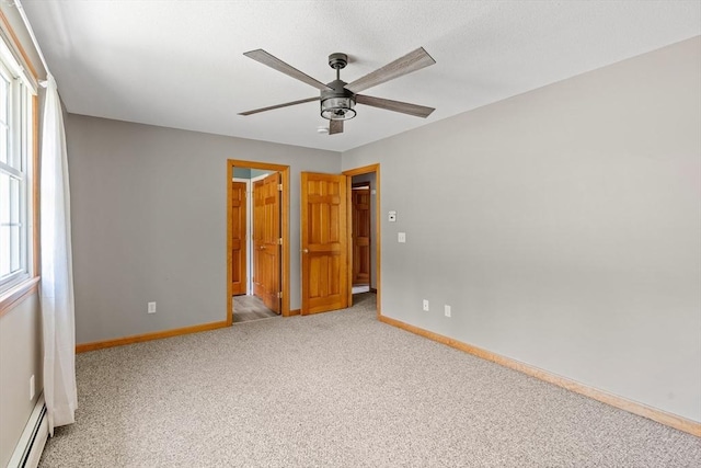 unfurnished bedroom featuring carpet flooring, a baseboard radiator, a ceiling fan, and baseboards