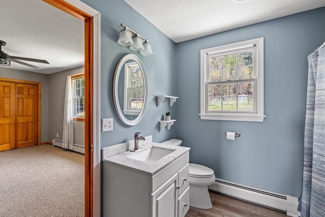 bathroom featuring a baseboard radiator, toilet, a ceiling fan, and vanity
