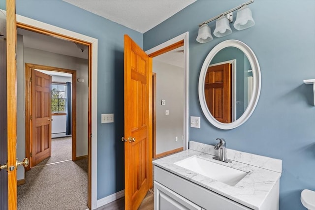 bathroom featuring a baseboard heating unit, baseboards, and vanity