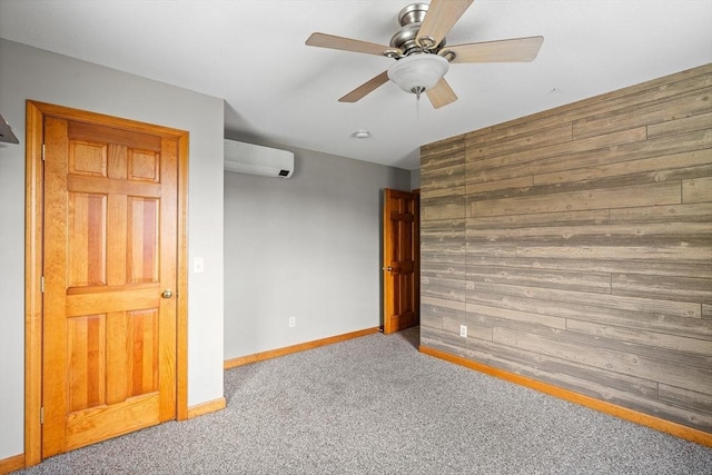 empty room with carpet, ceiling fan, wooden walls, an AC wall unit, and baseboards