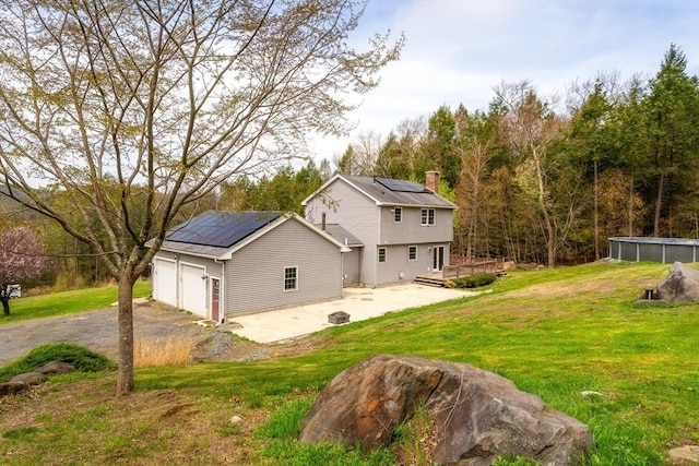 view of side of property with a deck, solar panels, a chimney, and a lawn