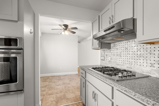 kitchen featuring under cabinet range hood, stainless steel appliances, decorative backsplash, baseboards, and ceiling fan