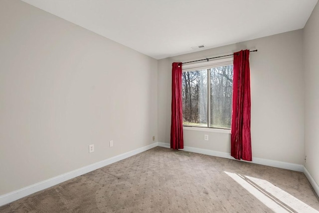 spare room with carpet flooring, baseboards, and visible vents