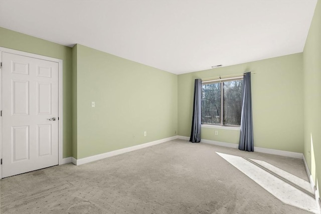 spare room featuring baseboards and light colored carpet