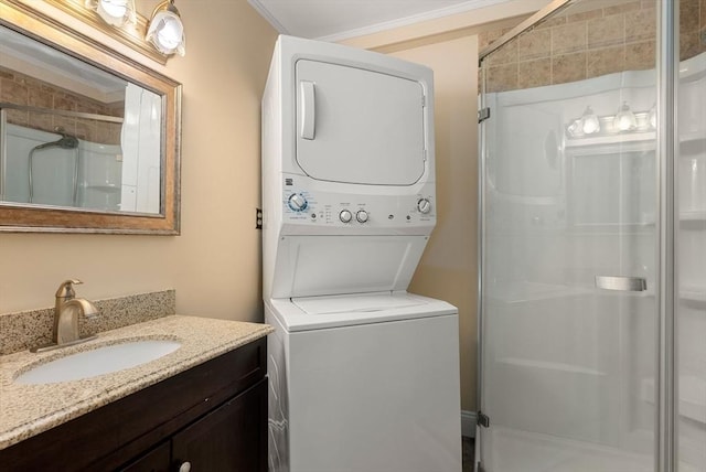 full bathroom featuring stacked washer / dryer, a shower stall, vanity, and ornamental molding