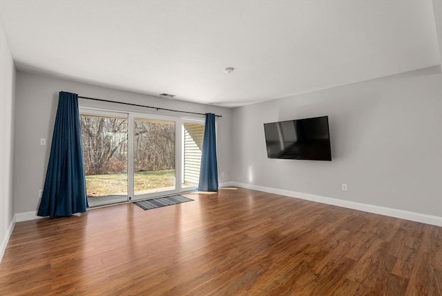 unfurnished living room with visible vents, wood finished floors, and baseboards