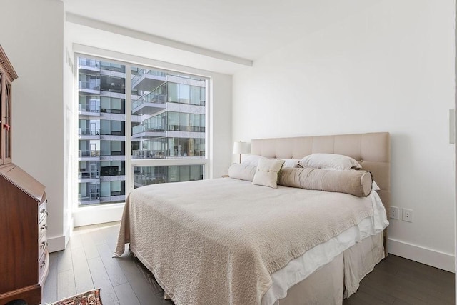 bedroom with baseboards and dark wood-style flooring