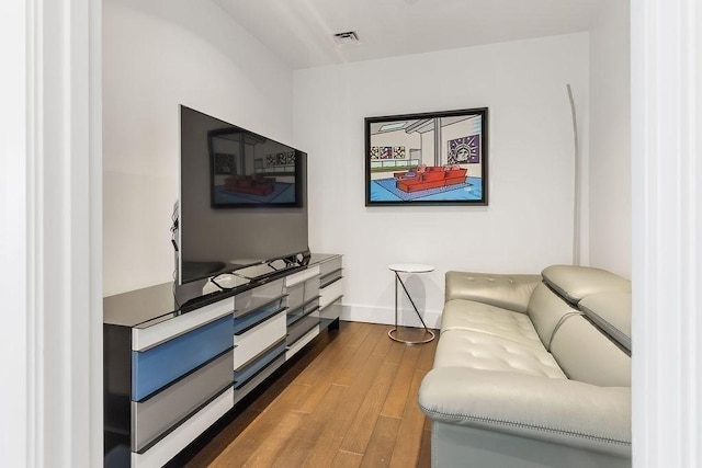 living room featuring visible vents, baseboards, and wood finished floors