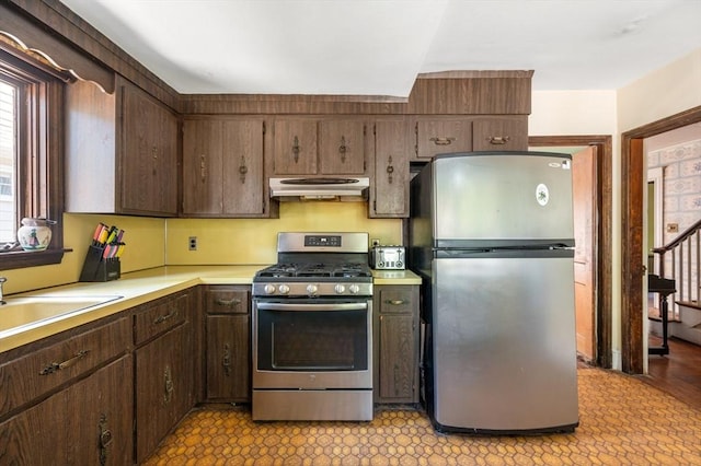 21 Otis St, Milton, MA 02186 - kitchen featuring stainless steel appliances, under cabinet range hood, a sink, light countertops, and dark brown cabinetry