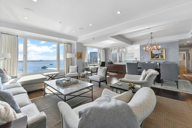 living room with dark wood-type flooring, a chandelier, and a water view