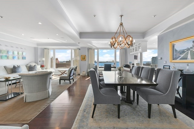 dining area with dark hardwood / wood-style flooring, a tray ceiling, and a chandelier