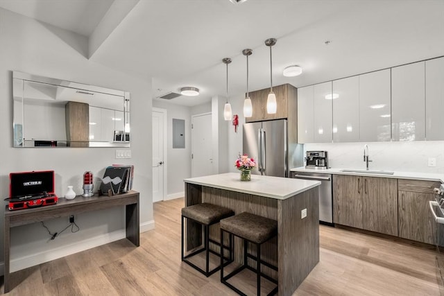 kitchen with a center island, sink, stainless steel appliances, decorative light fixtures, and white cabinets