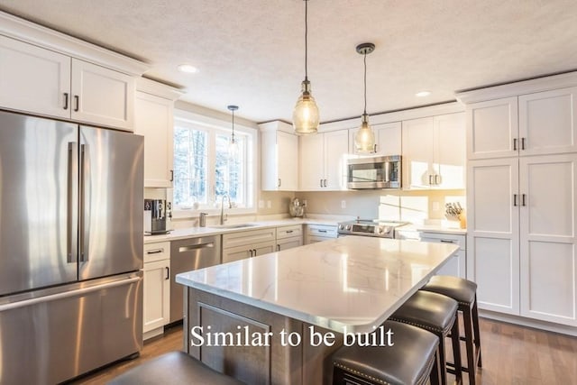 kitchen with white cabinetry, sink, a center island, hanging light fixtures, and appliances with stainless steel finishes