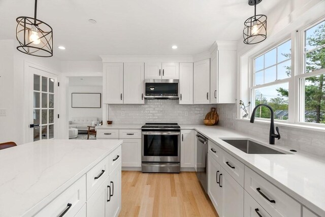 10 Sylvan Hill Xing, Haverhill, MA 01832 - kitchen featuring stainless steel appliances, a sink, tasteful backsplash, white cabinets, and light wood-type flooring