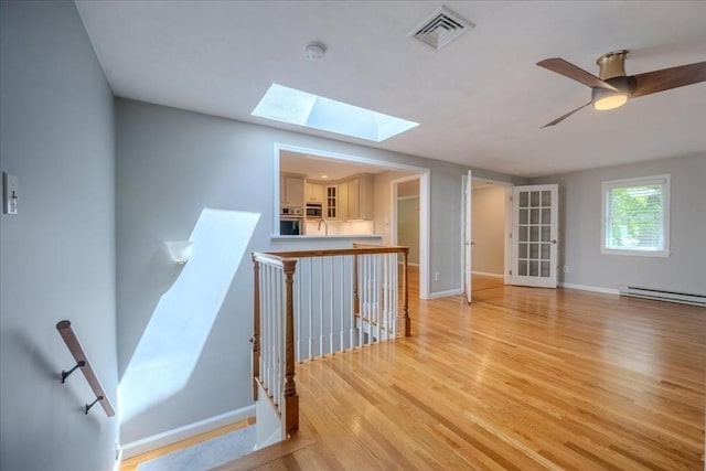 137 Naugler Ave, Marlborough, MA 01752 - unfurnished room with a skylight, baseboards, light wood-style floors, baseboard heating, and a ceiling fan