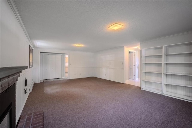 137 Naugler Ave, Marlborough, MA 01752 - unfurnished living room with a textured ceiling, a brick fireplace, dark colored carpet, crown molding, and a baseboard radiator