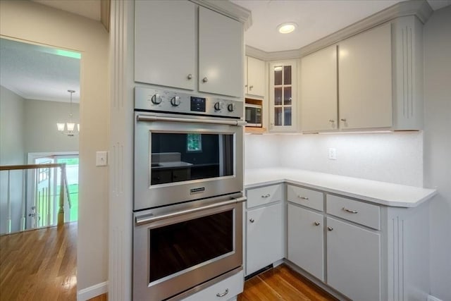 137 Naugler Ave, Marlborough, MA 01752 - kitchen featuring appliances with stainless steel finishes, wood finished floors, light countertops, a chandelier, and glass insert cabinets