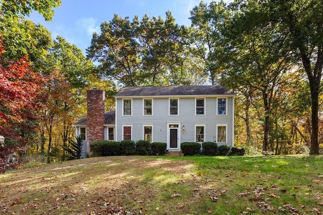 colonial home featuring a front yard and a chimney