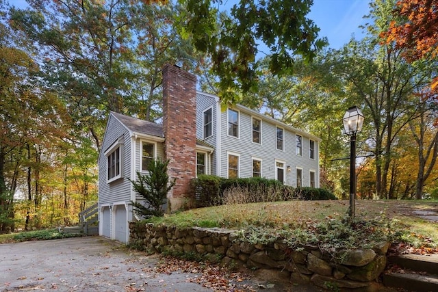 view of property exterior with a garage, driveway, and a chimney