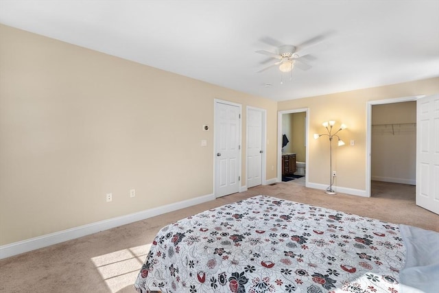 bedroom featuring light carpet, ensuite bathroom, a ceiling fan, and baseboards