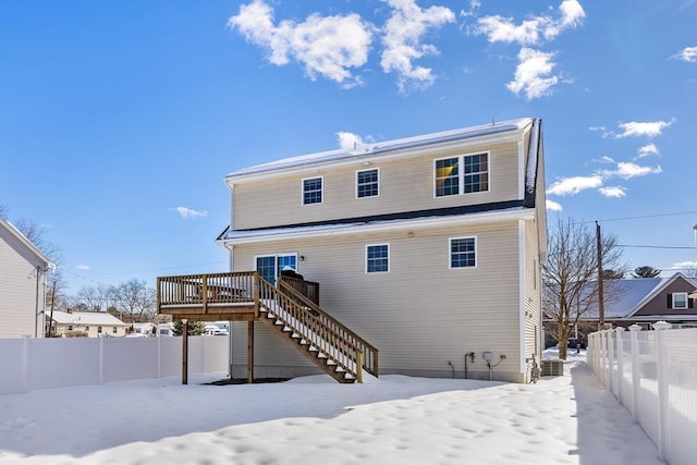 snow covered back of property with stairway, fence, and a wooden deck